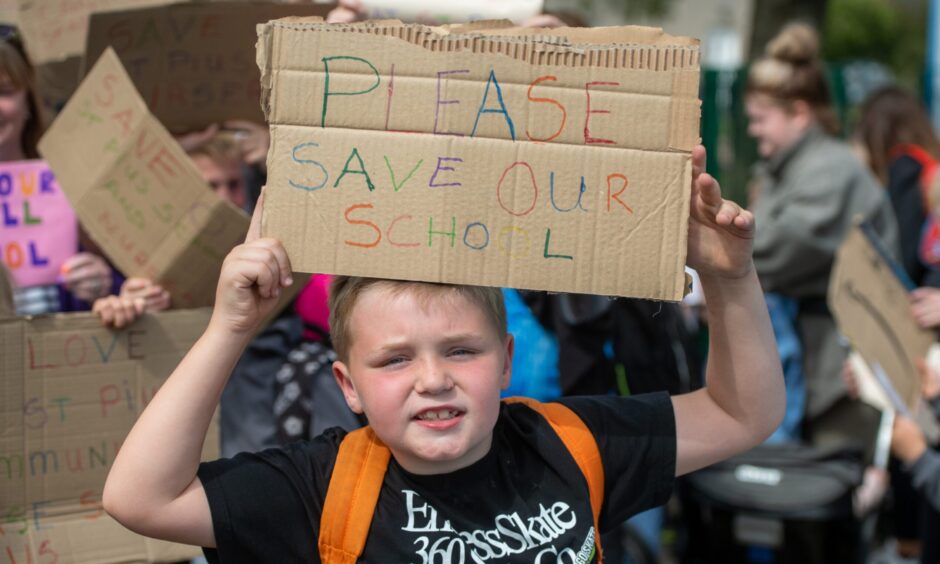 A boy at the St Pius school protest with a placard that reads 'Please save our school'.