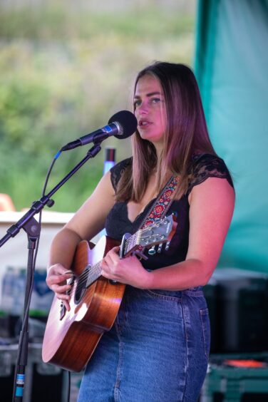 Justine Beverley plays a guitar on stage