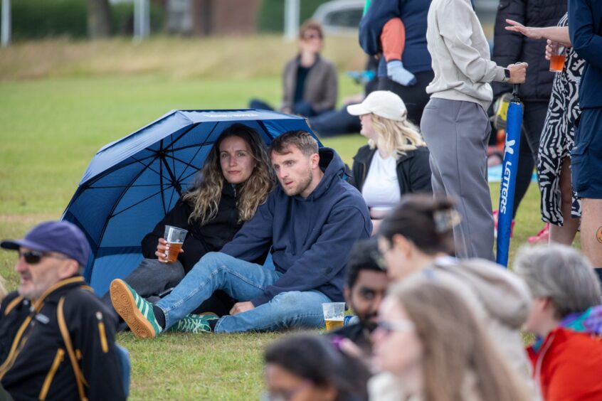 A man and woman shelter under an umbrella at Dundee's Westfest