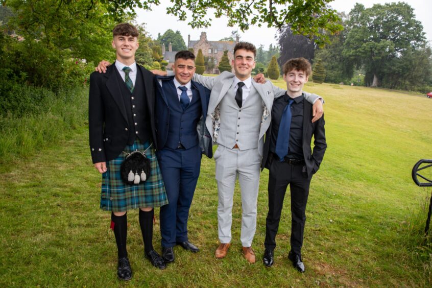 A group of boys wearing kilts and suits.