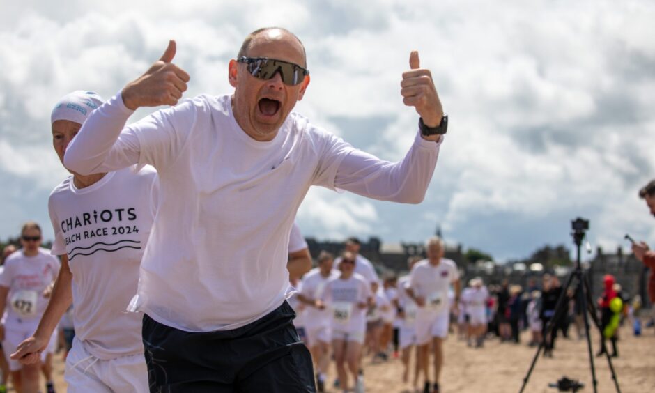 A competitor, with thumbs up and mouth open, enjoys the race.