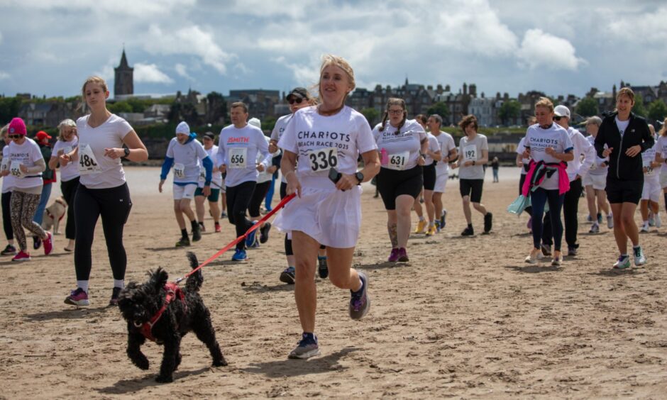A female racer with a black dog on a lead.