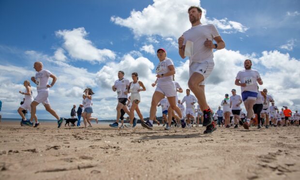 Runners dressed in white race along the West Sands in St Andrews for the Chariots of Fire Beach Race