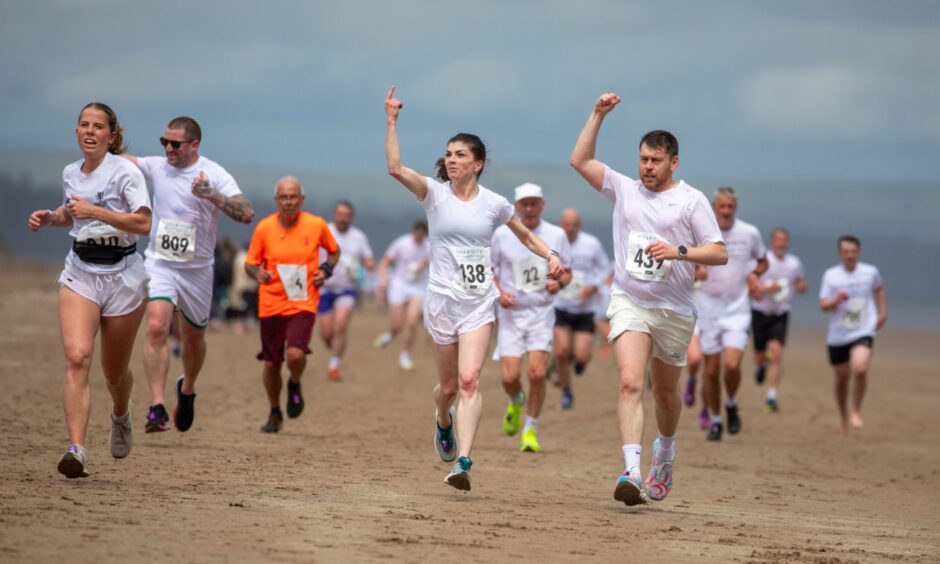 Competitors with arms aloft, sprint towards the finish line