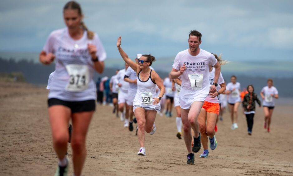 A runner waves to a spectator as the race continues