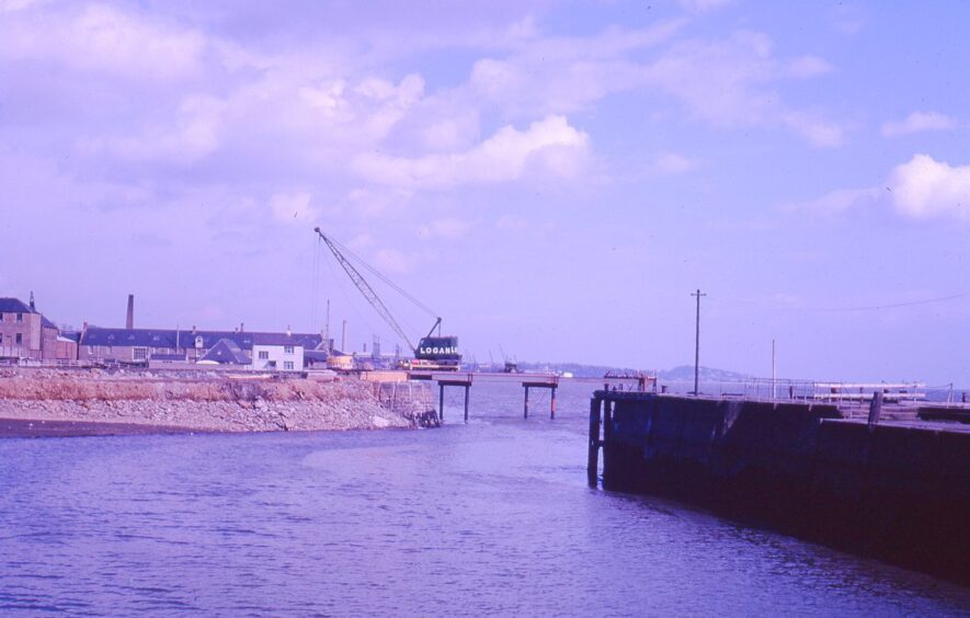 harbour walls in the foreground and a crane in the distance as work on the new road bridge starts in March 1963.