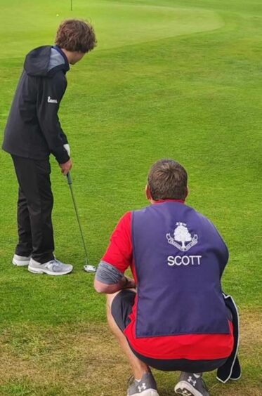 Scott, one of the caddies, watches golf talent Matt putt on one of the greens at Carnoustie. 