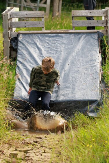 A boy makes a splash as he reaches the end of a slide. 