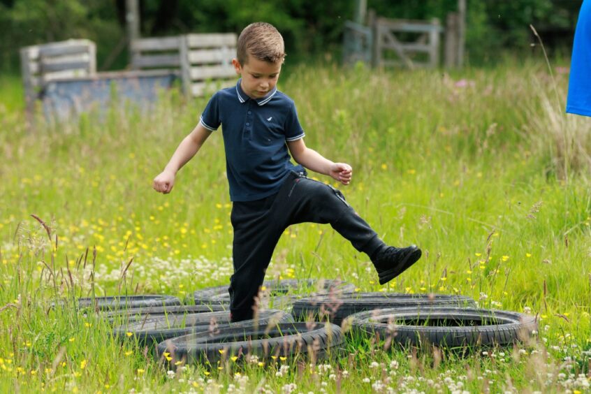 A boy tackles the obstacle of tyres on the ground. 