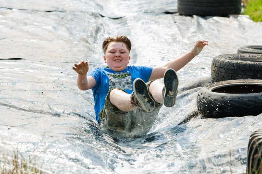 A boy slides down a tarpaulin.