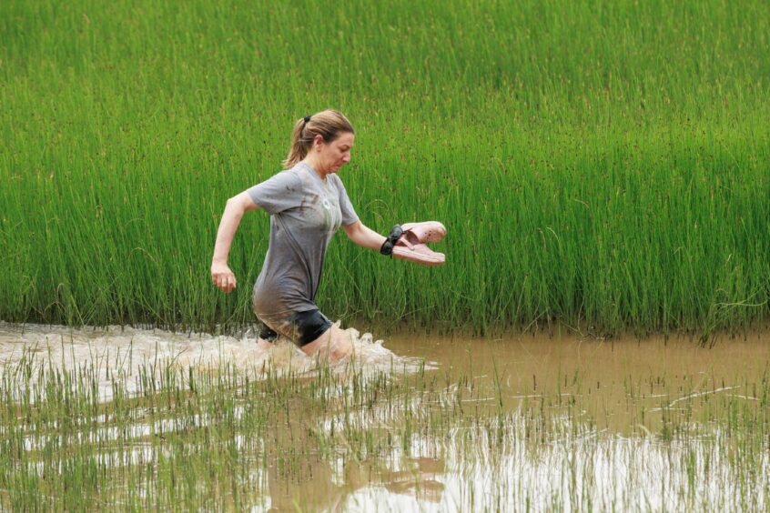 A woman running through a muddy pond. 