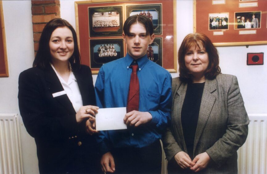Robbie receiving his prize from two teachers