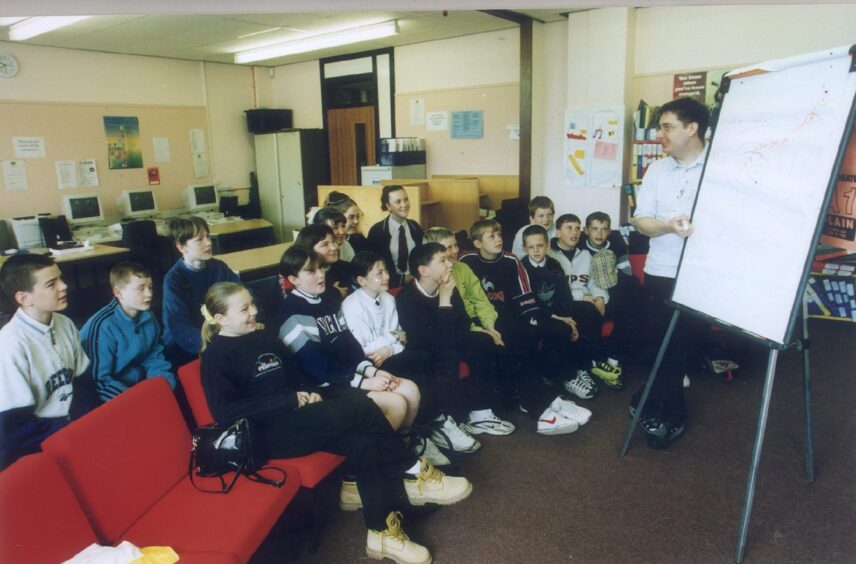 Derek Walker uses a whiteboard shows off the game to pupils