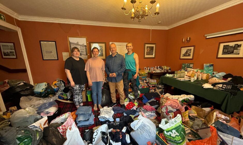 MP Pete Wishart with three other people in room surrounded by donations of food, clothes and household items at Salutation Hotel, Perth