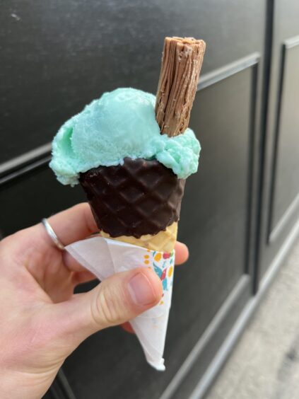 A hand holds a cone with a flake.