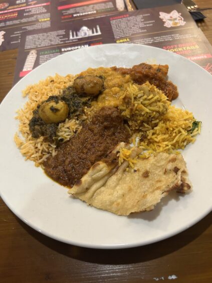 A plate of Indian food, including several curries, garlic naan and rice. 