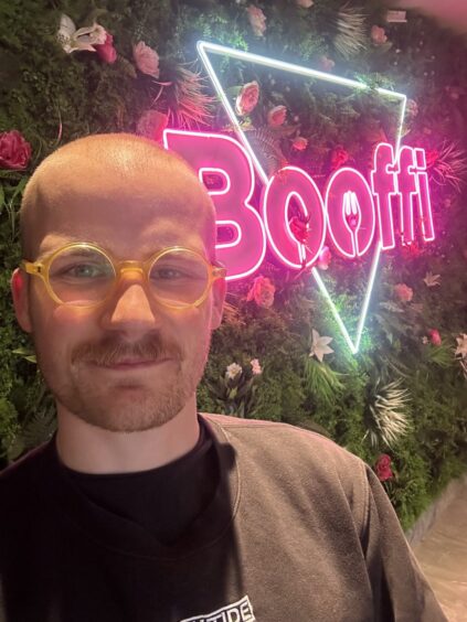 Jacob Smith posing in front of a neon sign.