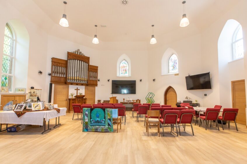A church hall with white walls and arched windows. 