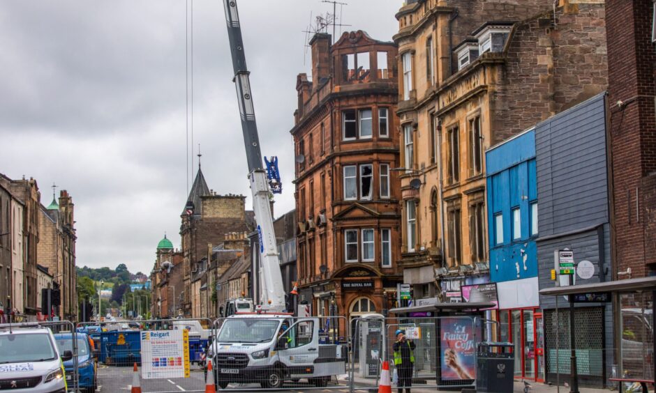 Aftermath of fire with crane outside building with burnt out roof and upper floor