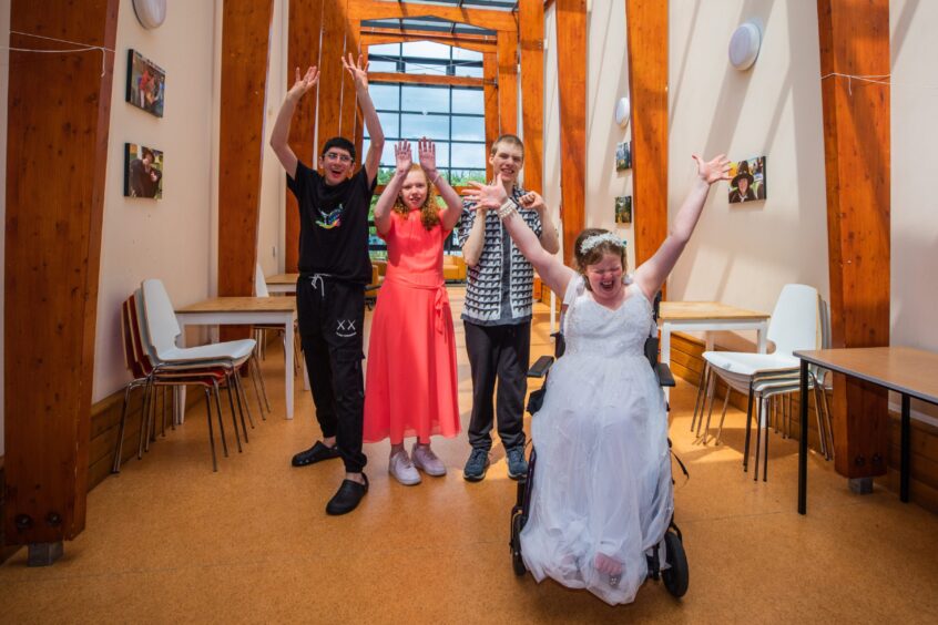 Four school leavers throw their hands in the air at the Fairview leavers' party 2025. 