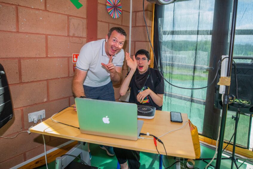 A DJ poses with a boy at the corner of the dancefloor. 