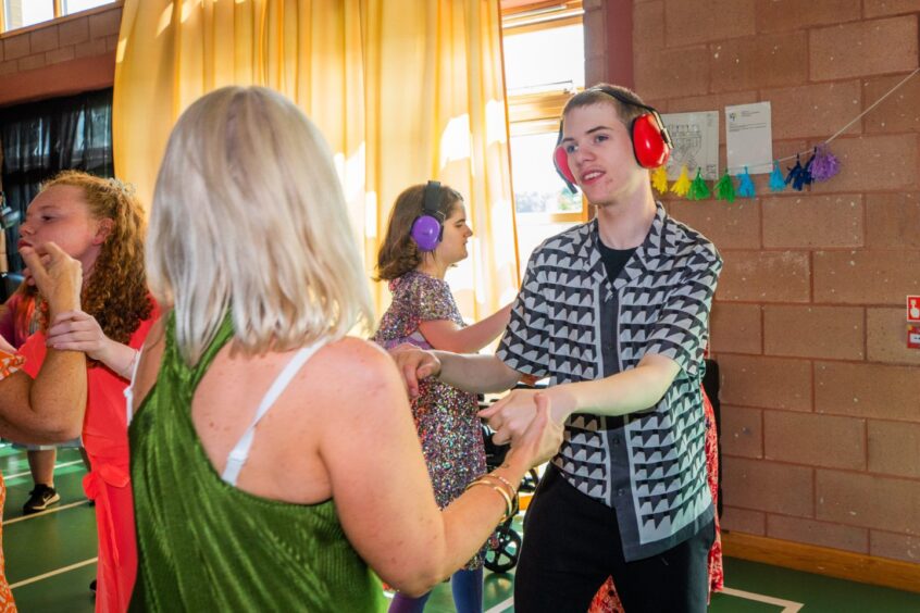 A woman dances with a boy with other party-goers around them. 