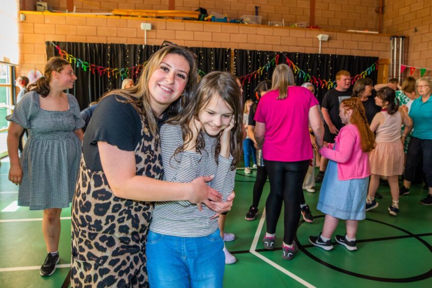 A woman and girl smile as a party goes on around them. 