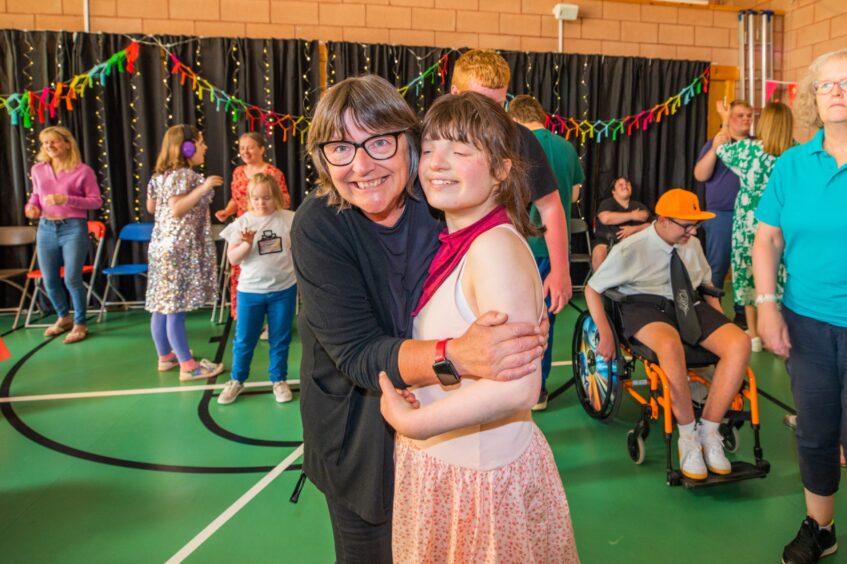 A woman and girl smile for a photo as a party goes on around them. 