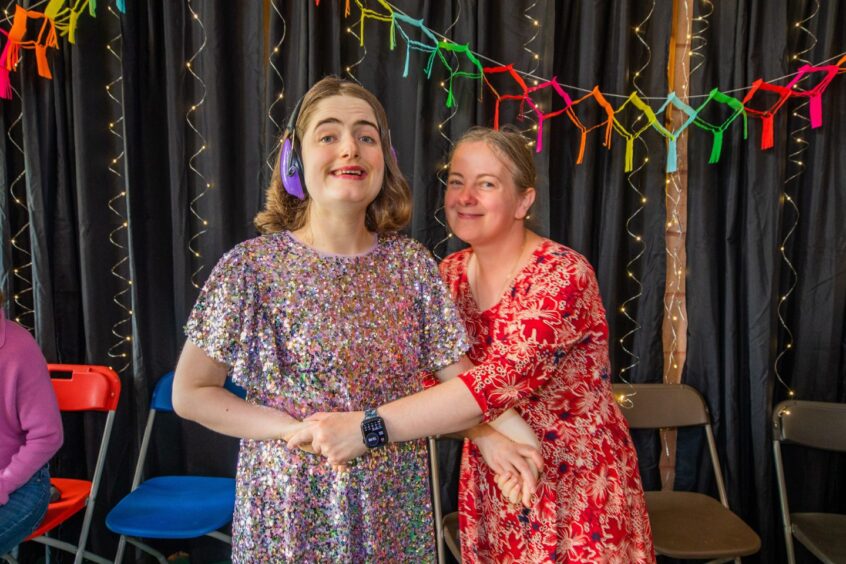 An woman and girl smiling in a gym hall festooned with decorations. 