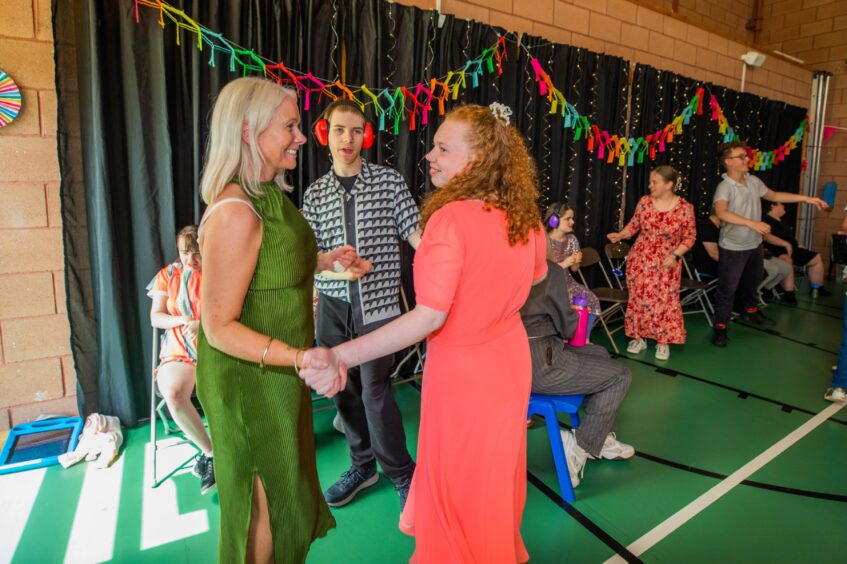 Pupils dancing in a gym hall festooned with decorations. 