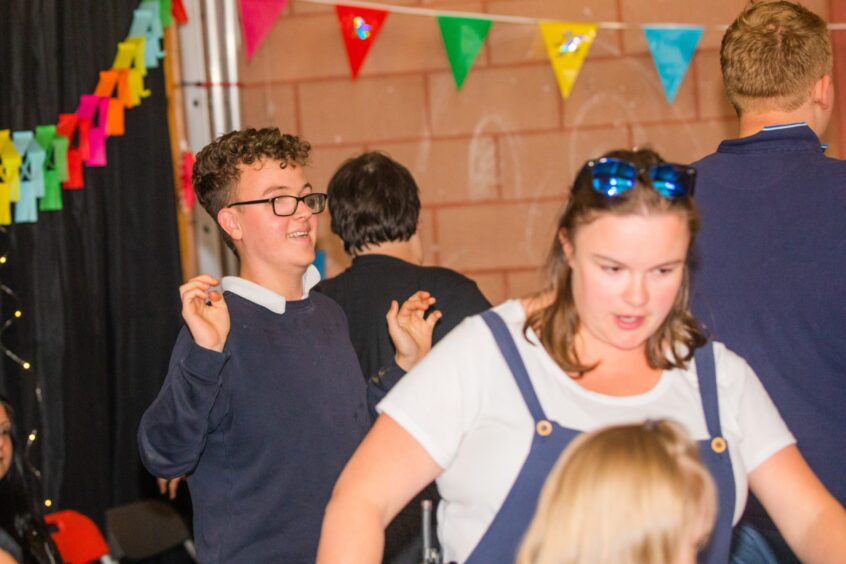 Pupils dancing in a gym hall festooned with decorations. 