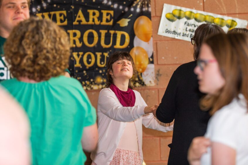Pupils dancing in a gym hall festooned with decorations. 