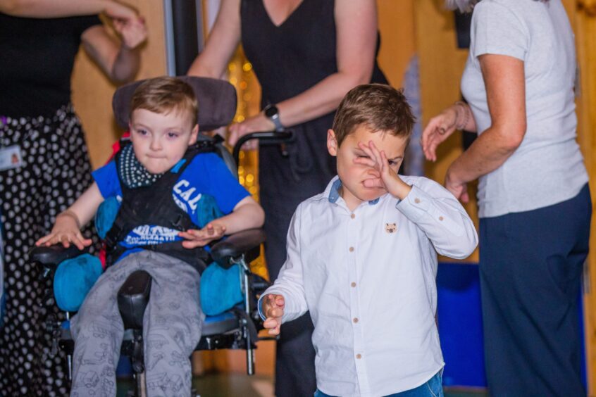 Two boys, one in a wheelchair, enjoying a party. 