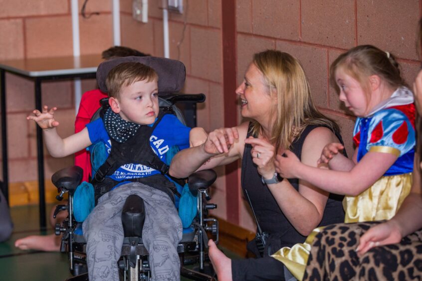 A woman interacts with two children at a party. 