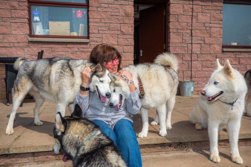 Heather cuddling two dogs.