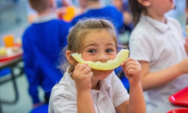 Primary 2 pupil looking happy with her melon for pudding at Pitteuchar West Primary School.