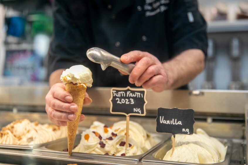 A person serving a cone at The Perfect Scoop.
