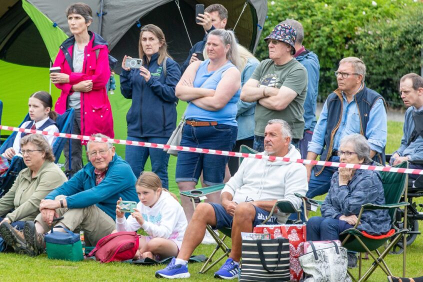Spectators watch from the sidelines. Some film the action on their phones.