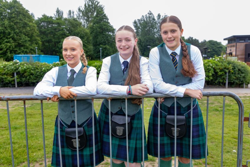 Morla Bruce, Charlotte Rawlin and Ksenia Mann from Dundee High School stand at the barrier watching the opposition.