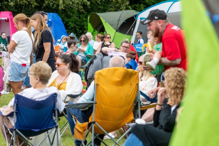Parents and family members sit in camping chairs watching the action.