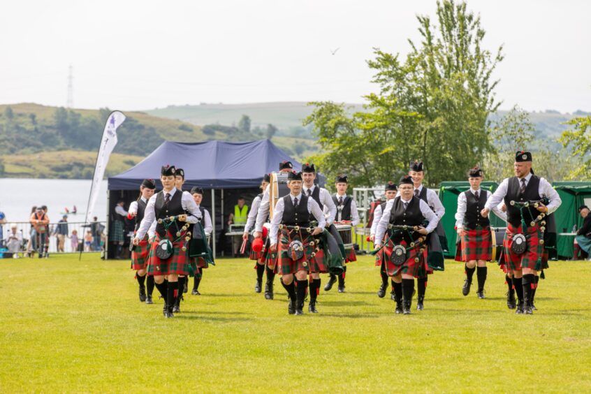 A pipe band walks off the field after performing.