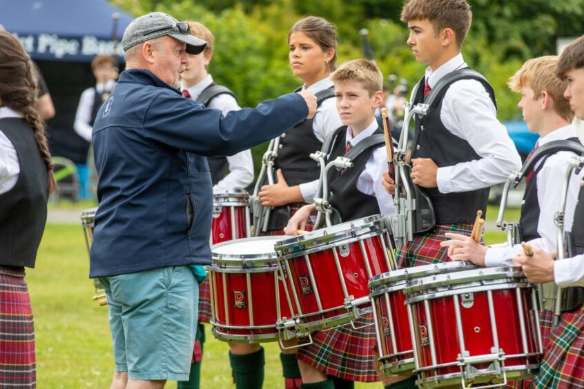 An adult speaks to pupils from George Watson's College Pipe Band.
