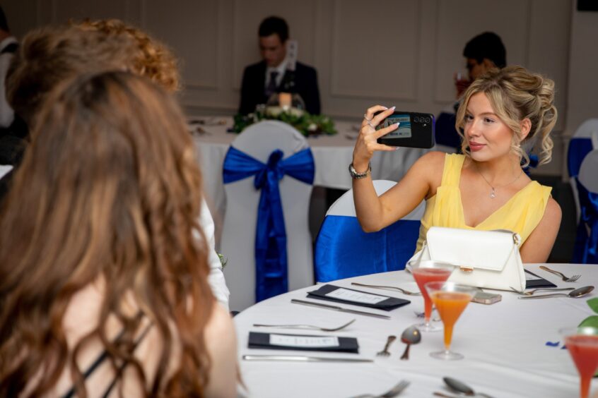 An attendee takes a picture at the prom. 