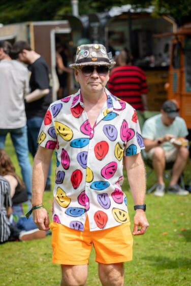 A man in orange shorts and a shirt covered in multicoloured smiley faces.