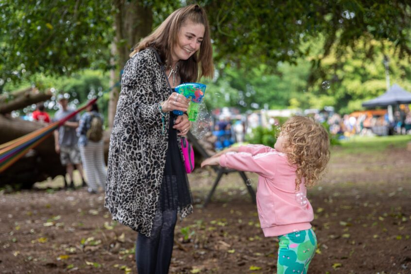 Mandy Morgan fires a bubble gun and Robyn chases the bubbles.