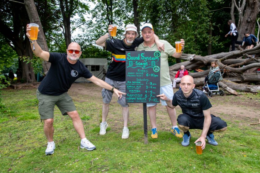 Ganghaus band members point to their 5-7pm slot on a blackboard listing the acts playing the Sound System stage.