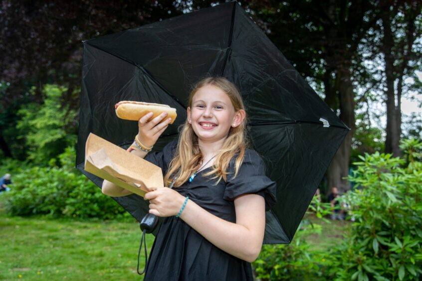 Orla Quigley holds an umbrella to keep herself and her hotdog dry.