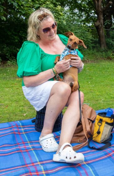 Donna holds small dog Milly on her lap.