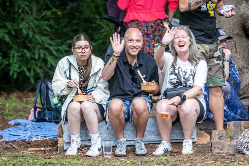 Spectators wave as they enjoy some food and drinks.
