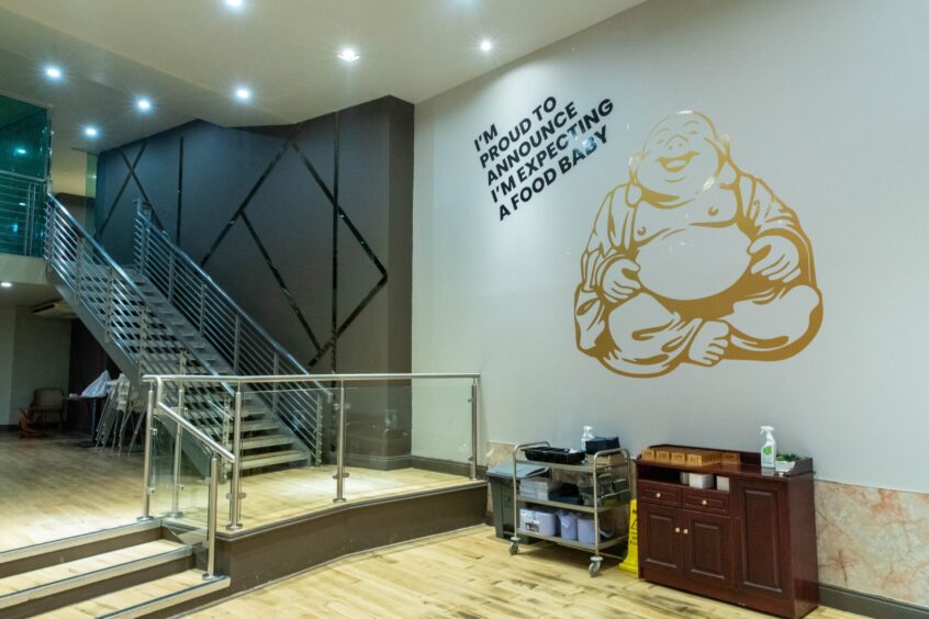 A mural of a Buddha alongside the slogan "I'm proud to announce I'm expecting a food baby."